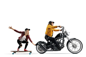 Man riding a chopper and a young female riding a skateboard