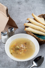Simple comfort chicken soup on a grey table in a restaurant, top view