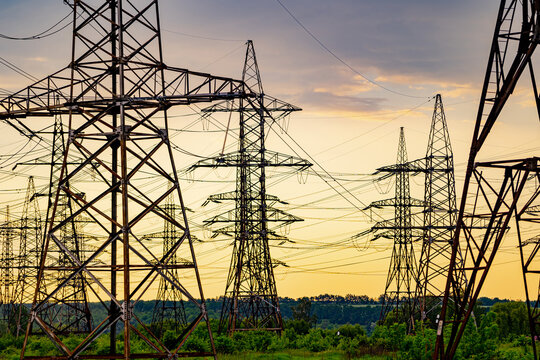 High voltage electrical substation over sunset background with transformers.