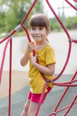 Foto op Canvas Schattig 6 jaar oud meisje dat het net beklimt in de speeltuin © Albert Ziganshin