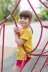 Foto op Canvas schattig meisje dat het net in de speeltuin beklimt © Albert Ziganshin