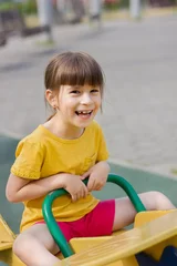 Fotobehang schattig meisje lacht en rolt op een schommel in een kleuterschool © Albert Ziganshin