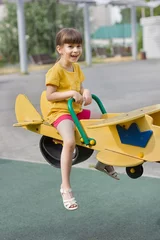 Poster Schattig meisje lacht en rolt op een wip op een speelplaats © Albert Ziganshin