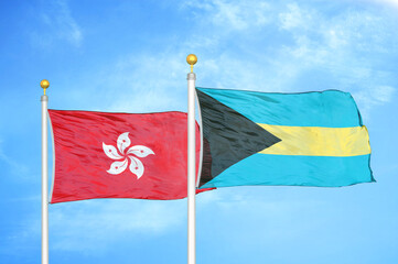 Hong Kong and Bahamas  two flags on flagpoles and blue cloudy sky