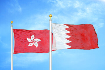 Hong Kong and Bahrain  two flags on flagpoles and blue cloudy sky