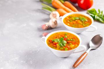 Vegetable soup with spices and basil on a light stone background. Сopy space.