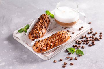 Traditional french eclairs with chocolate on a light stone background.