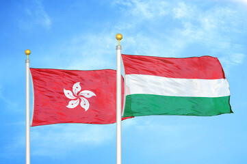 Hong Kong and Hungary two flags on flagpoles and blue cloudy sky