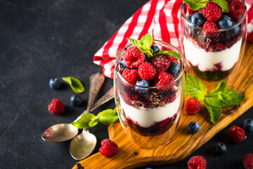 Parfait with granola, jam and fresh berries in the glass jar.