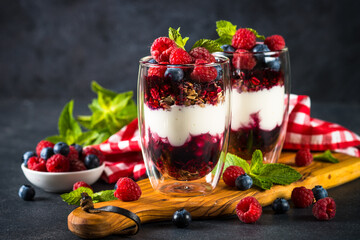 Parfait with granola, jam and fresh berries in the glass jar.