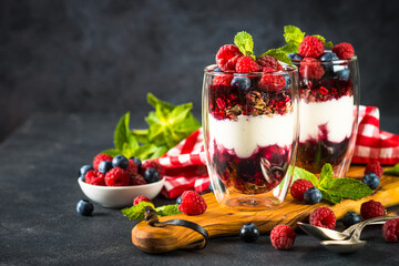 Parfait with granola, jam and fresh berries in the glass jar.