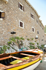 Fototapeta na wymiar boat near a stone wall with small windows in an old corner of europe