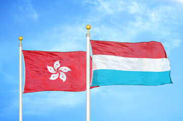 Hong Kong and Luxembourg two flags on flagpoles and blue cloudy sky