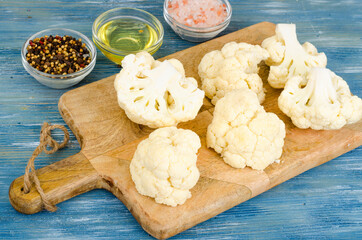 Inflorescences of fresh cauliflower on kitchen wooden board.