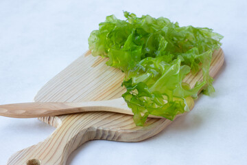 fresh green leaves of Ulva seaweed, for making salad, on a wooden Board, light background