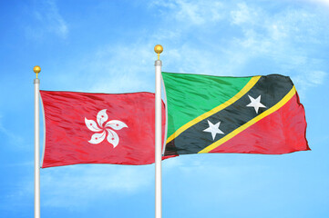 Naklejka na ściany i meble Hong Kong and Saint Kitts and Nevis two flags on flagpoles and blue cloudy sky