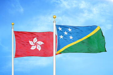 Naklejka na ściany i meble Hong Kong and Solomon Islands two flags on flagpoles and blue cloudy sky