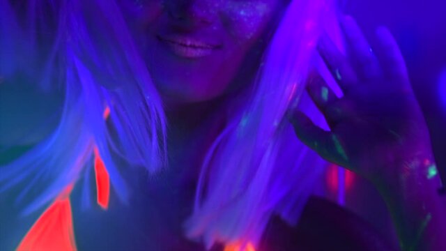 Disco Fashion model dancing woman in neon light, beautiful model girl colorful bright fluorescent make-up, painted skin, Body Art design, disco female in UV, colorful make up. Night club. Slow motion 