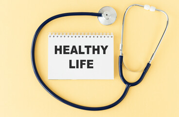 On a purple background a stethoscope with yellow list with text Healthy Life