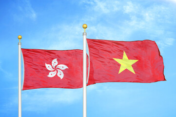 Hong Kong and Vietnam two flags on flagpoles and blue cloudy sky