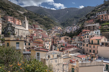 View of Riomaggiore village, first & most southern of Cinque Terre coastal villages, located in a small & narrow valley, as seen from west seaside towards east, La Spezia, Liguria region, Italy.