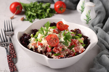 Tomato salad with cottage cheese, green onions, parsley and spices in white bowl on a gray background