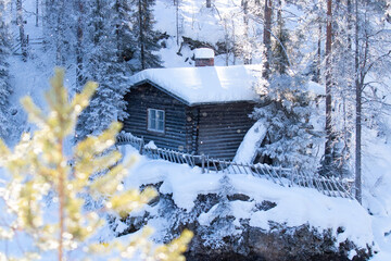 A small cozy wintery cabin by the river in Finnish taiga forest, Northern Europe. 