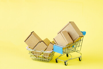 Paper shopping bags in a shopping cart on yellow background, concept online shopping.
