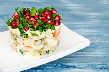 Served salad decorated with greens and pomegranate seeds.