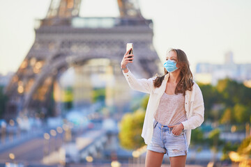 Girl standing near the Eiffel tower in Paris and wearing protective face mask during coronavirus outbreak