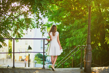 Woman in white dress walking on famous Montmartre hill in Paris, France at early morning