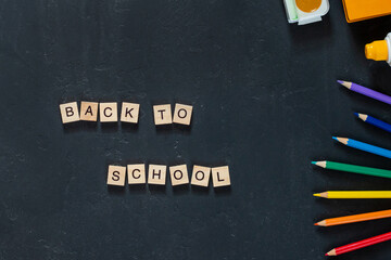 the inscription "BACK to SCHOOL" in wooden letters with shadows on a black background
