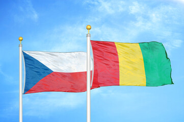 Czech and Guinea two flags on flagpoles and blue cloudy sky