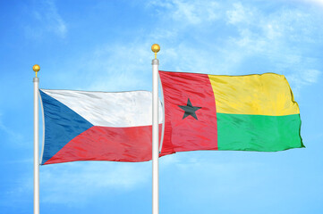 Czech and Guinea-Bissau two flags on flagpoles and blue cloudy sky