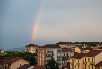 Turin, Piedmont, Italy. June 2020. After a summer storm in the northern suburbs, a rainbow emerges from the roof of a small house on the horizon and embraces the city.