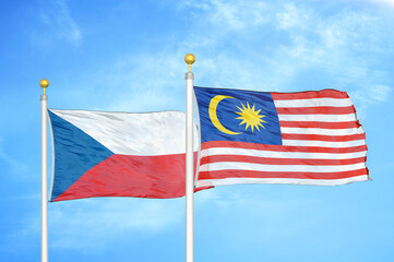 Czech and Malaysia two flags on flagpoles and blue cloudy sky
