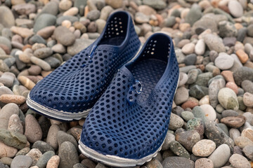 Blue rubber bathing slippers. Beach shoes on pebbles, near the sea.