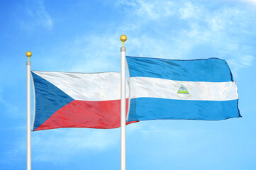 Czech and Nicaragua two flags on flagpoles and blue cloudy sky