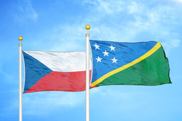 Czech and Solomon Islands two flags on flagpoles and blue cloudy sky