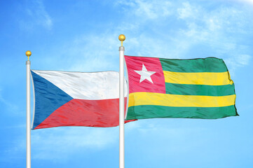 Czech and Togo two flags on flagpoles and blue cloudy sky