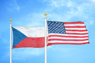 Czech and United States two flags on flagpoles and blue cloudy sky