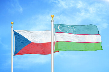Czech and Uzbekistan two flags on flagpoles and blue cloudy sky