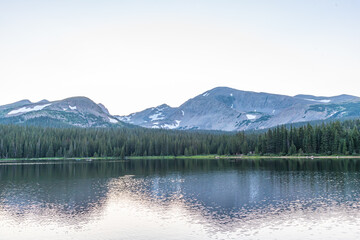 Mountains with snow near lake with evergreen forest trees and hiking trails