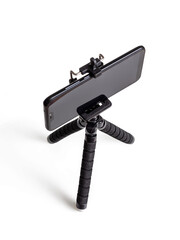 Black mini tripod with fixed black phone on white background