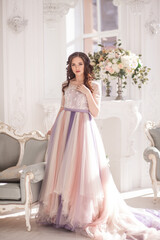 Fototapeta premium Bride in color wedding dress. Beautiful model in a beautiful wedding dress in a white photo studio. Portrait of an attractive girl in a beautiful interior.