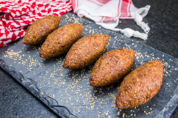 Delicious Lebanese  food, kibbeh (kibe) on black slate stone and granite background with traditional keffyeh.