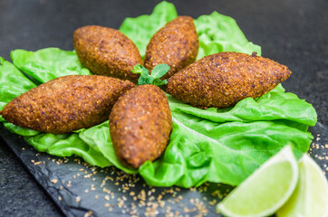 Delicious Lebanese  food, kibbeh (kibe) on black slate stone and granite background.