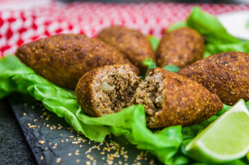 Delicious Lebanese  food, kibbeh (kibe) with sauces and lemon on black slate stone and granite background with traditional keffyeh.