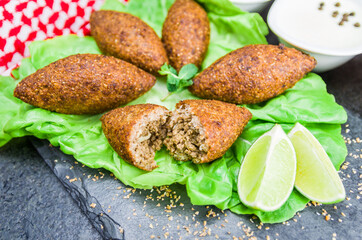 Delicious Lebanese  food, kibbeh (kibe) with sauces and lemon on black slate stone and granite...