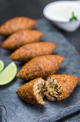 Delicious Lebanese  food, kibbeh (kibe) on black slate stone and granite background.